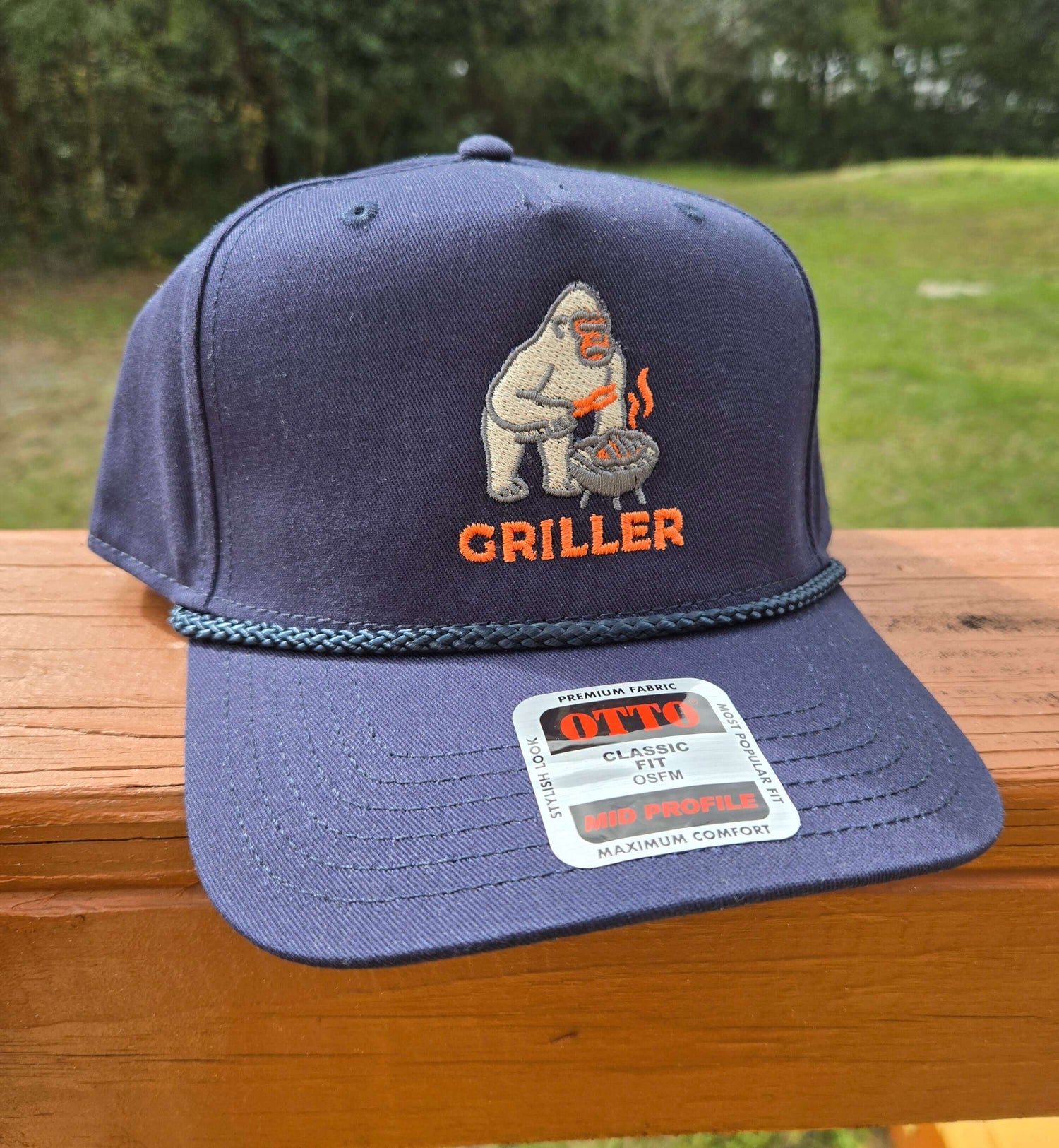 Navy baseball cap with embroidered design of a gorilla grilling with the text 'griller' below the design.  