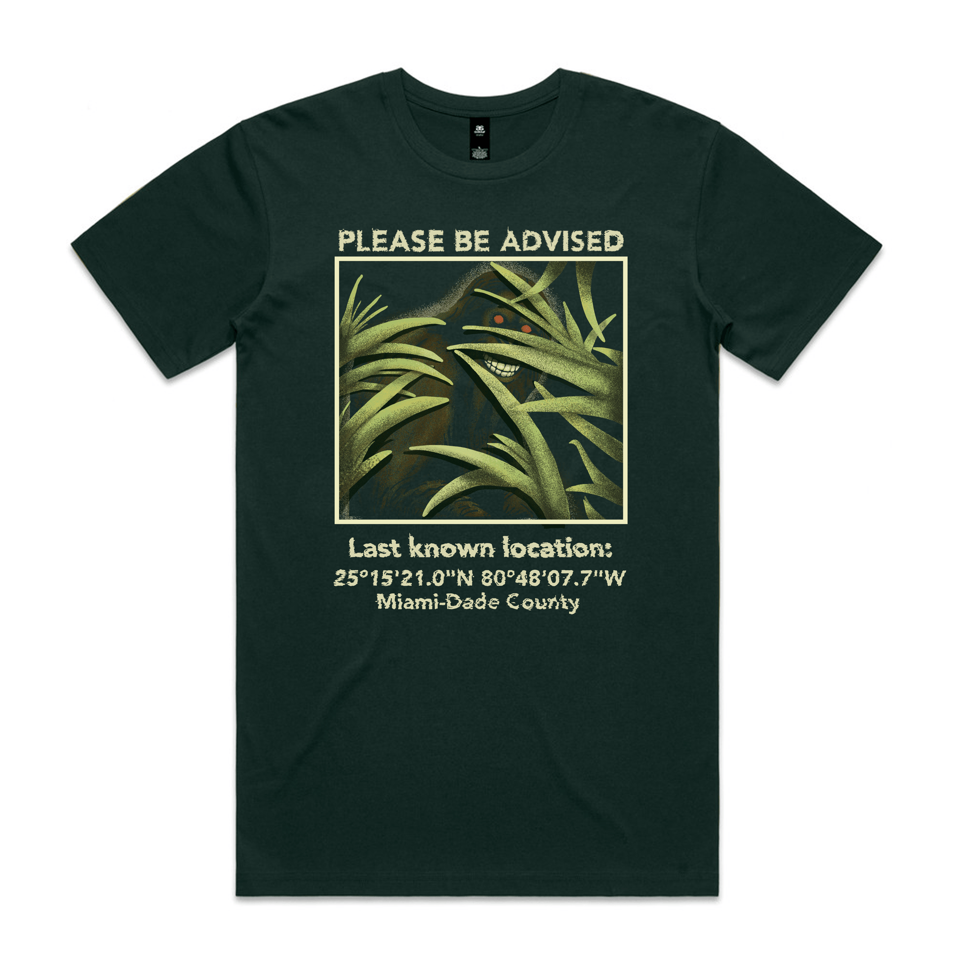 Forest green t-shirt with a picture of a skunk ape surrounded by the text 'please be advised, last known location' with coordinates in Miami-Dade County. 