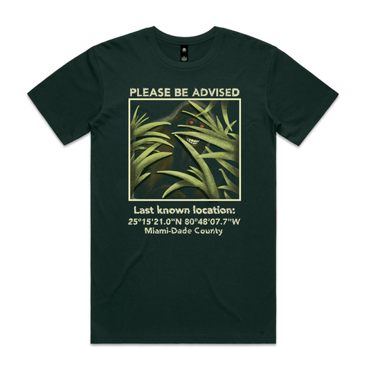 Forest green t-shirt with a picture of a skunk ape surrounded by the text 'please be advised, last known location' with coordinates in Miami-Dade County. 